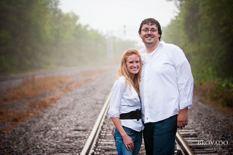 Smiling couple in rain on train tracks